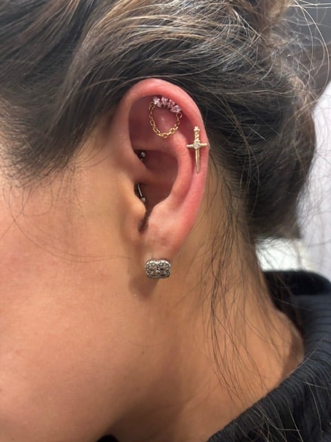 Close-up side view of womans ear showing multiple piercings including decorative and hoop earrings