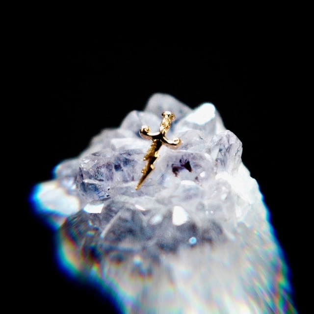 Small golden lizard standing atop a clear crystalline mineral stone against a black background