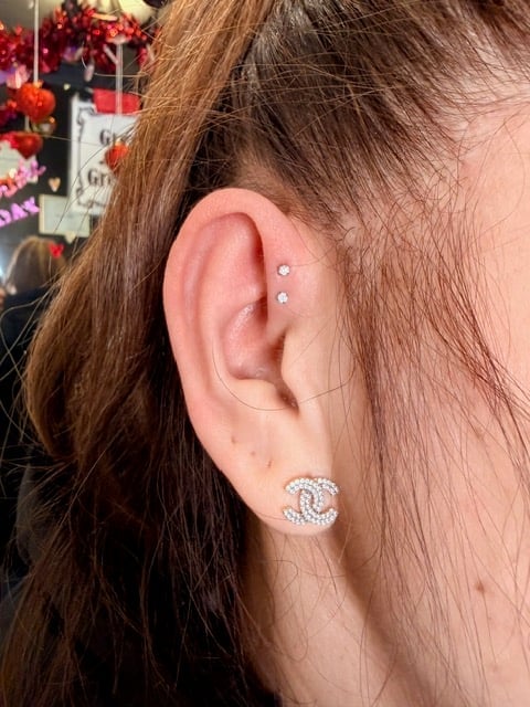 Close-up of a persons ear with multiple piercings, wearing crystal stud earrings and a decorative spiral earring