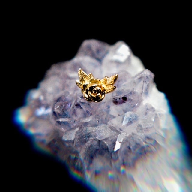 Gold winged rose pendant on translucent purple amethyst crystal against black background